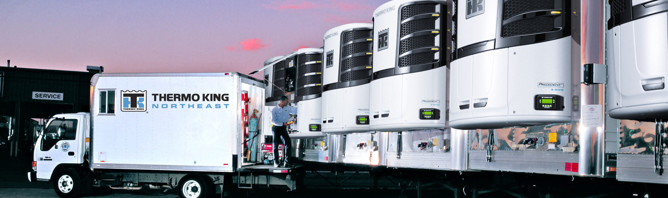 line up of reefer units on trailers with a thermo king service member in a truck taking a look at them
